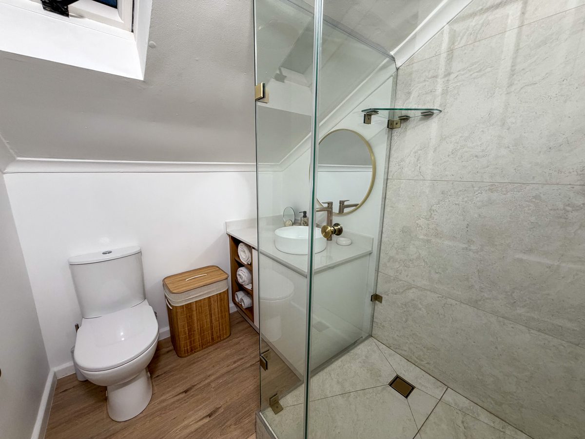 Renovated bathroom with a glass shower, vanity and round mirror