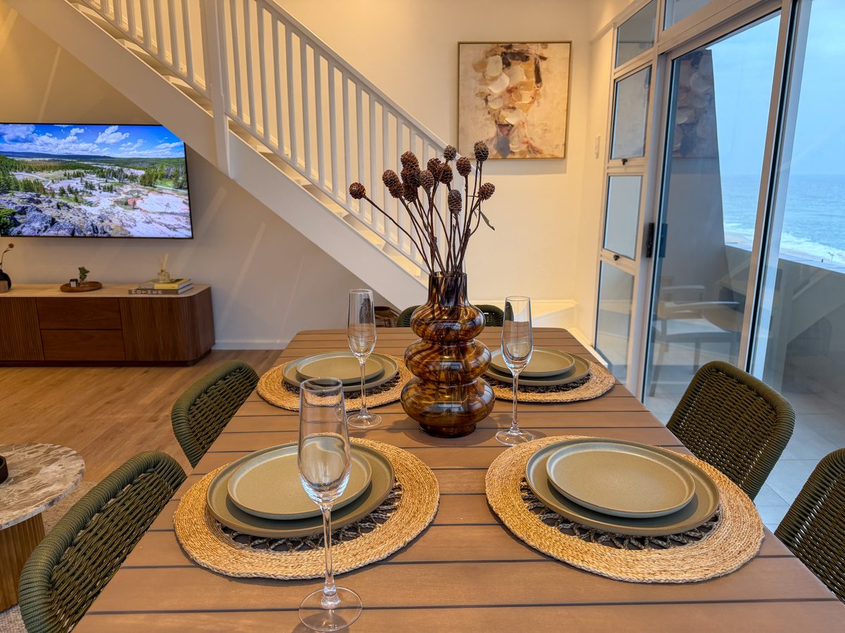 Dining table set for four beside the windows and loft staircase
