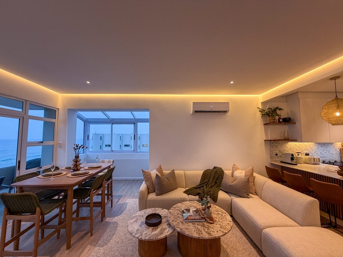 801's open-plan lounge in the evening, with a corner sofa, dining table and warm ceiling lighting